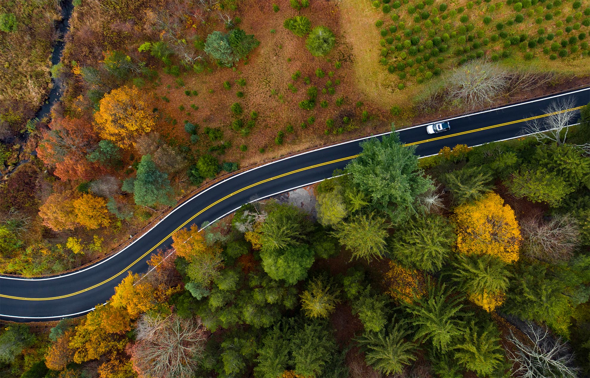 Photograph of a birds eye view of a car on an Autumn road in NJ taken with a drone