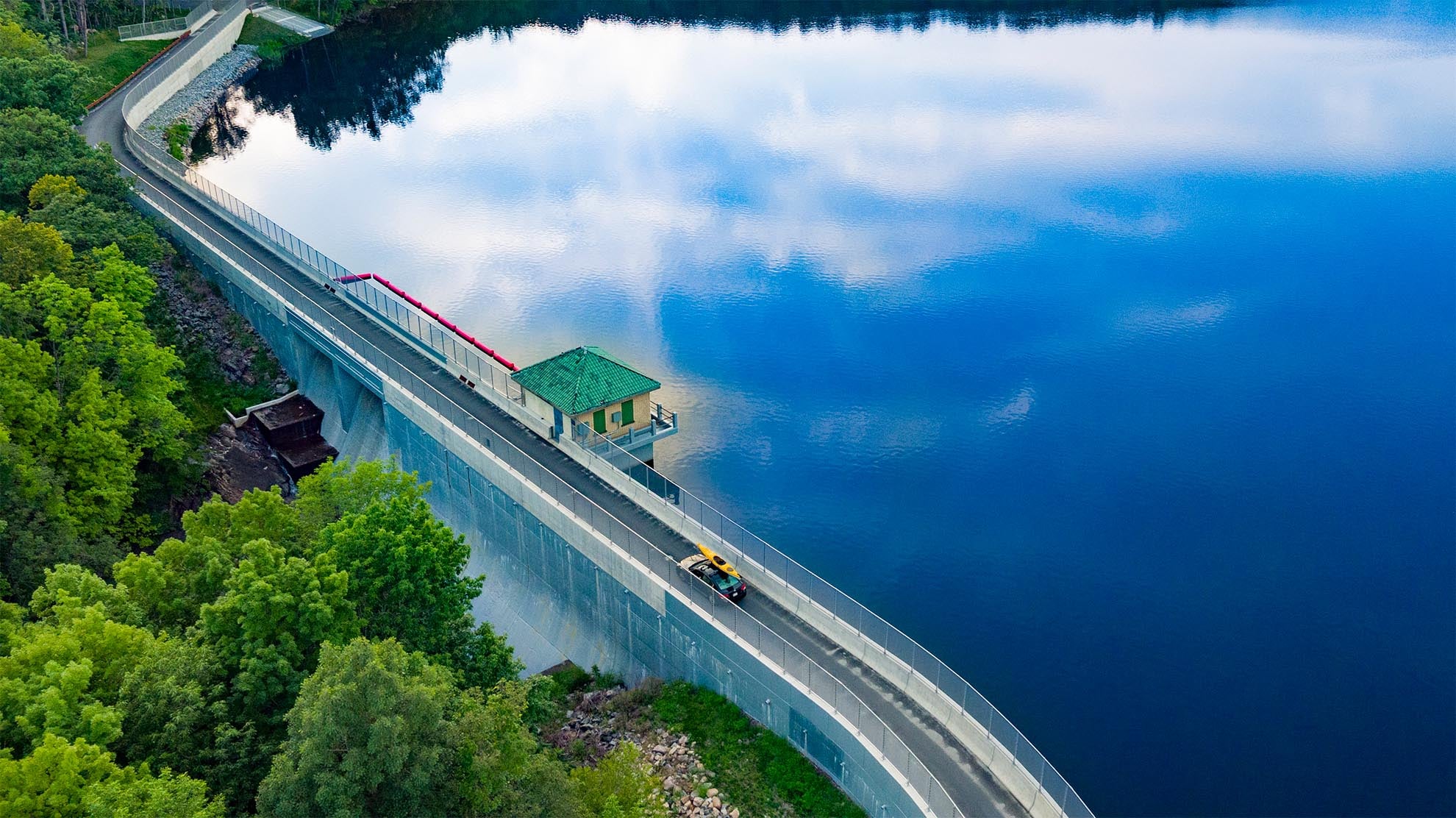 Drone Photograph of car with yellow kayak on roof crossing the Split Rock Dam