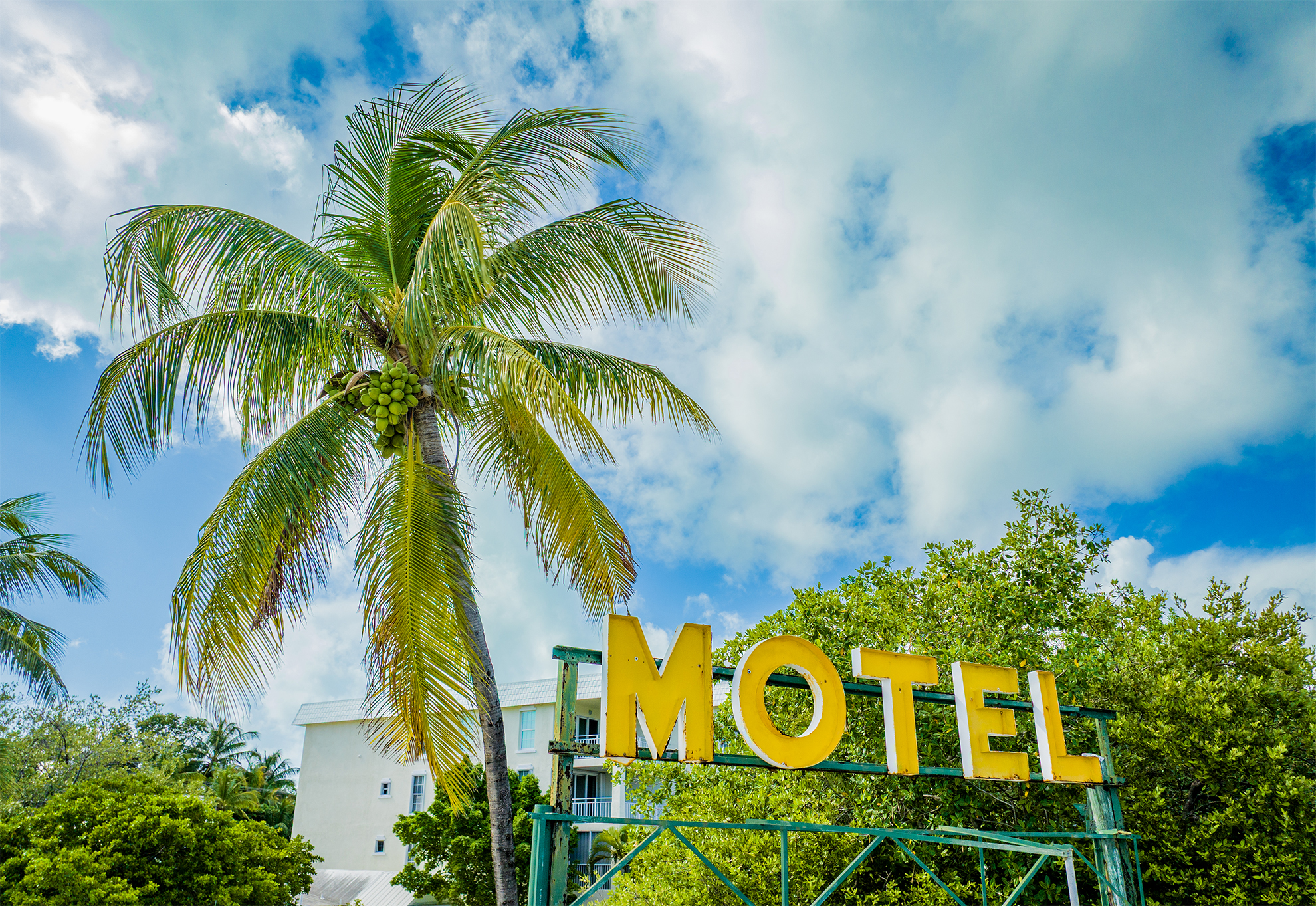 Drone photo of old yellow neon motel sign with coconut tree in Key West FL